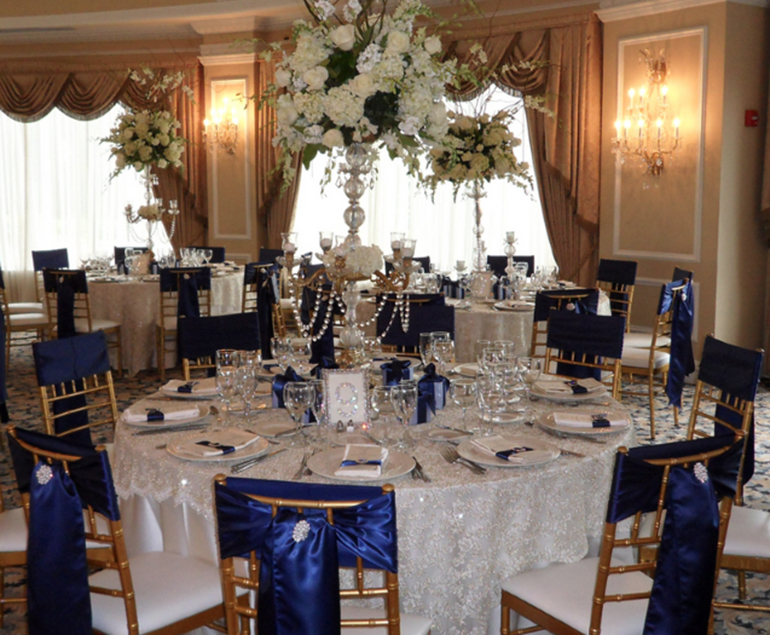 Royal blue chair ribbons with white tablecloth and white centerpiece. 